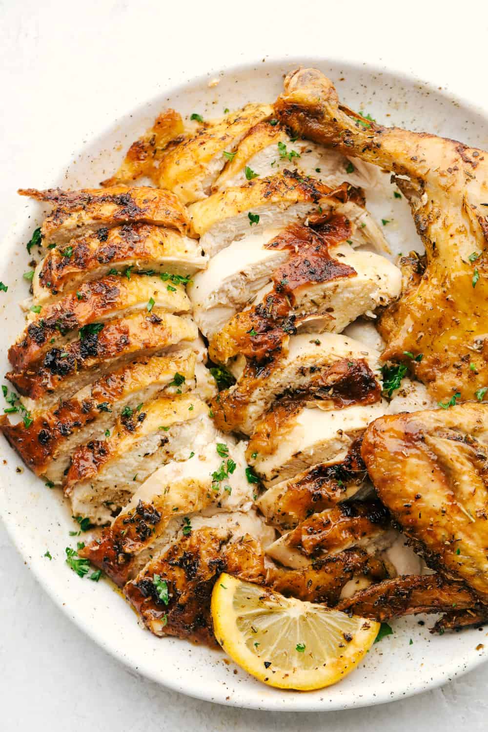 Pollo jugoso en rodajas en un plato con una rodaja de limón.